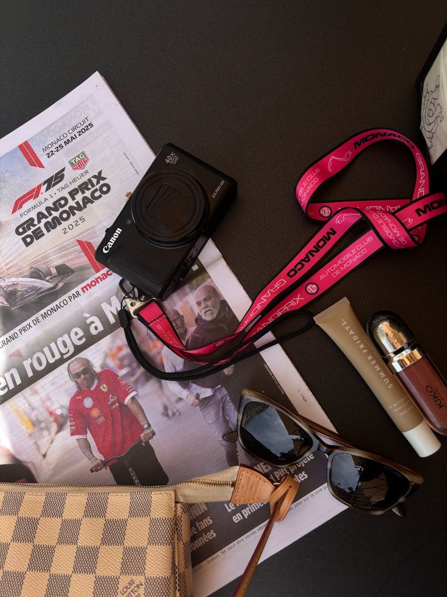 Flat lay of a camera, sunglasses, and accessories on a table with a Monaco Grand Prix theme.